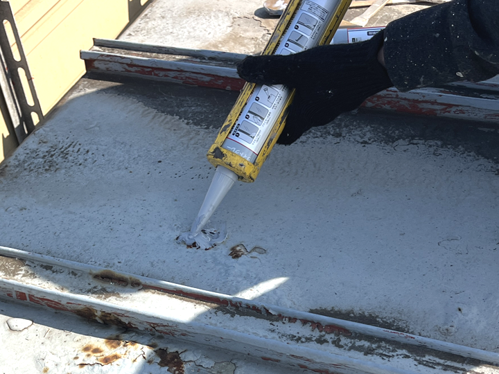 金属屋根の穴をコーキングで補修している様子